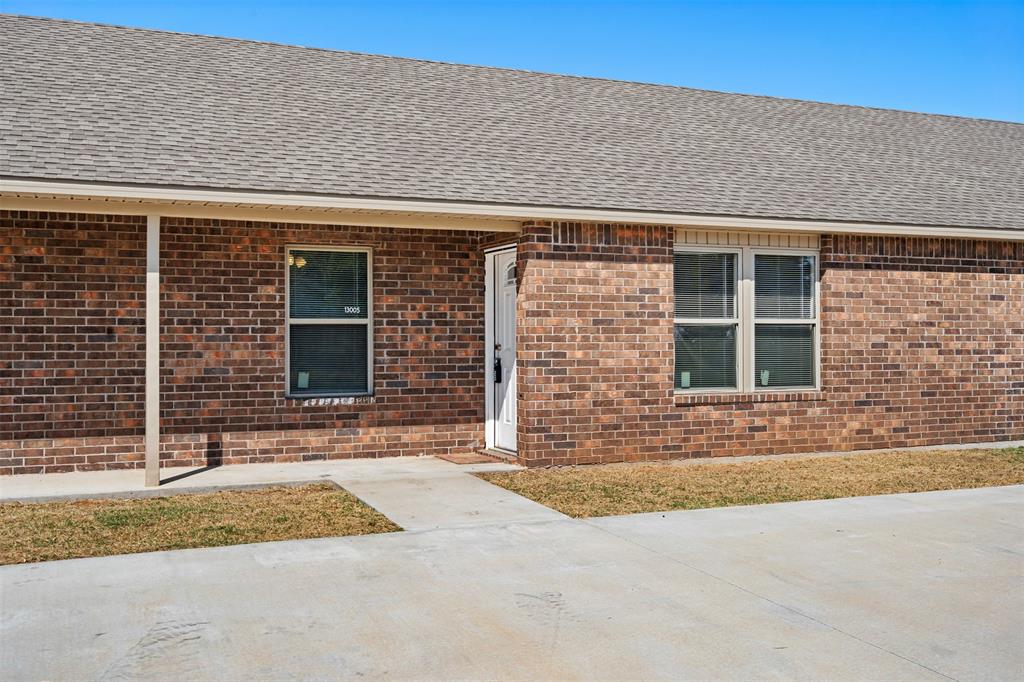 View of front of home featuring roof with shingles and brick siding