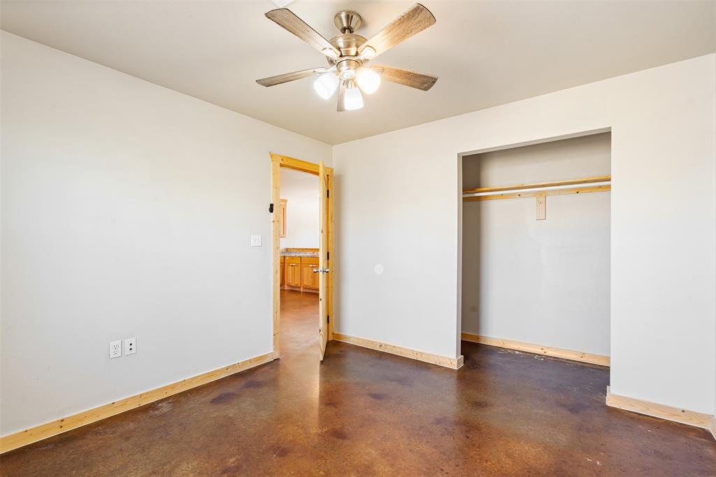 13001 Owen Lane, Unit 13005 Thackerville, OK 73459 - Photo 12 of 15 Unfurnished bedroom featuring finished concrete flooring, a closet, and a ceiling fan