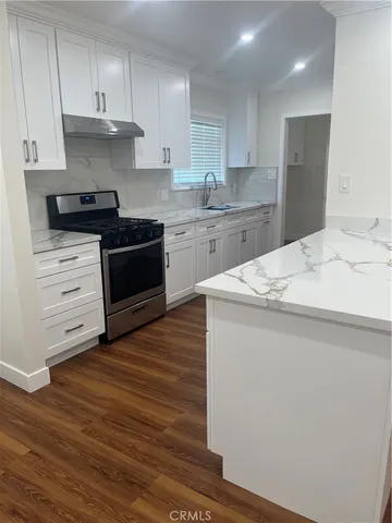 a kitchen with granite countertop a stove a sink and a refrigerator