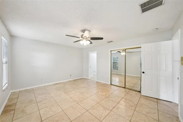 an empty room with wooden floor fan and windows
