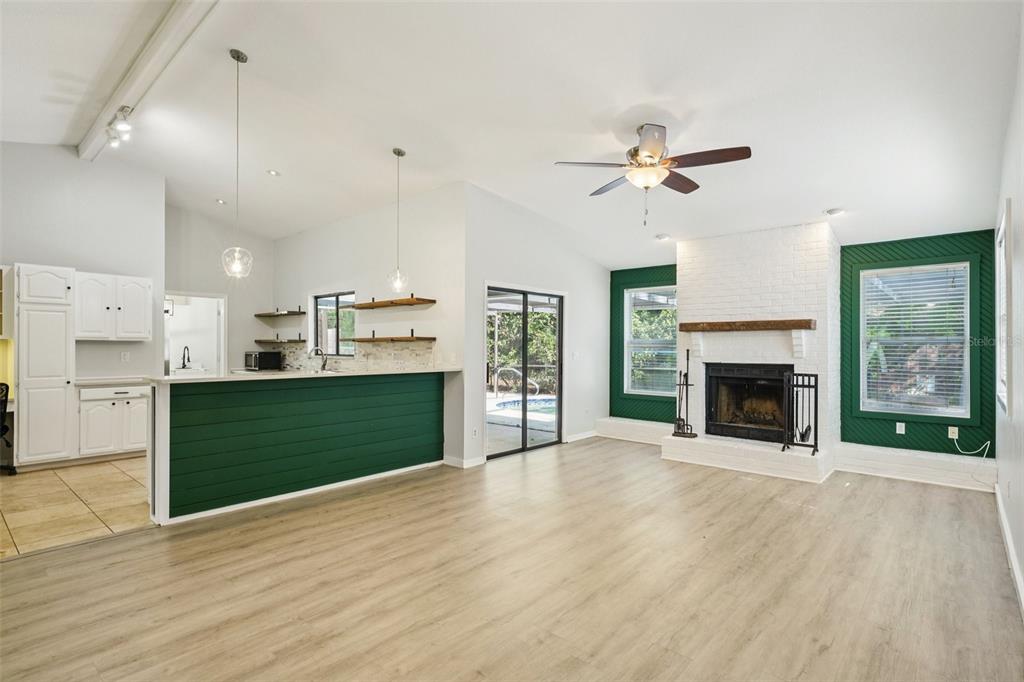 3109 Lake Valencia Lane East Palm Harbor, FL 34684 - Photo 5 of 59 a view interior of a kitchen with a fireplace a ceiling fan and wooden floor