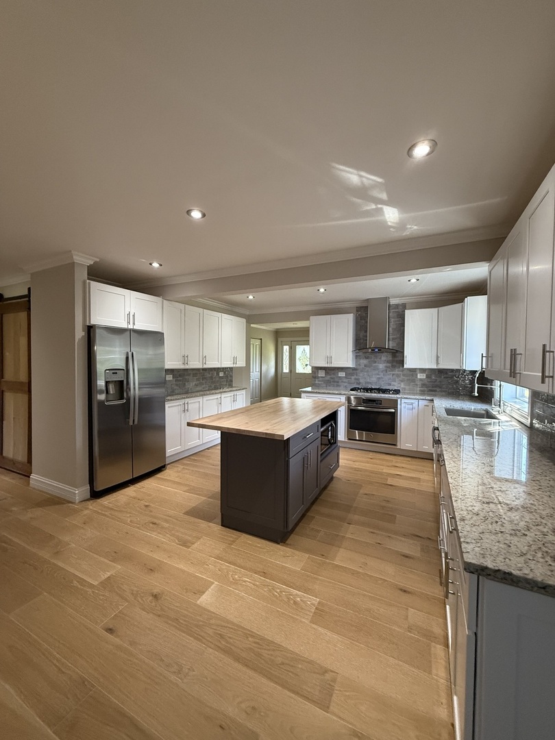 8144 Sunset Road Willowbrook, IL 60527 - Photo 2 of 8 a large kitchen with kitchen island a sink a counter top stainless steel appliances and cabinets