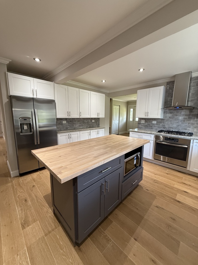 8144 Sunset Road Willowbrook, IL 60527 - Photo 3 of 8 a large kitchen with stainless steel appliances granite countertop a large counter top and a stove top oven