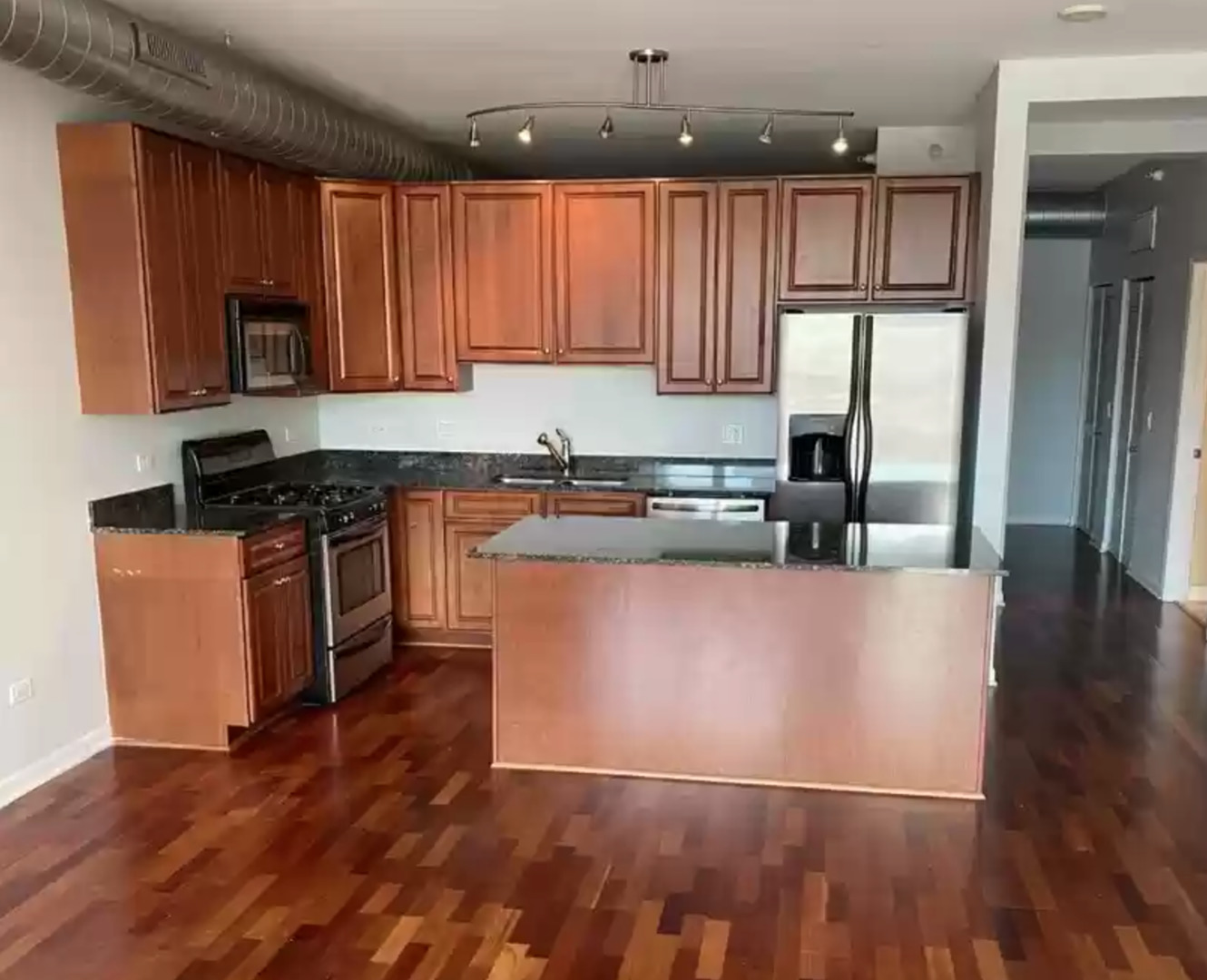 1200 West Monroe Street, Unit 603 Chicago, IL 60607 - Photo 2 of 11 a kitchen with stainless steel appliances granite countertop a refrigerator a stove top oven a sink and dishwasher with wooden floor