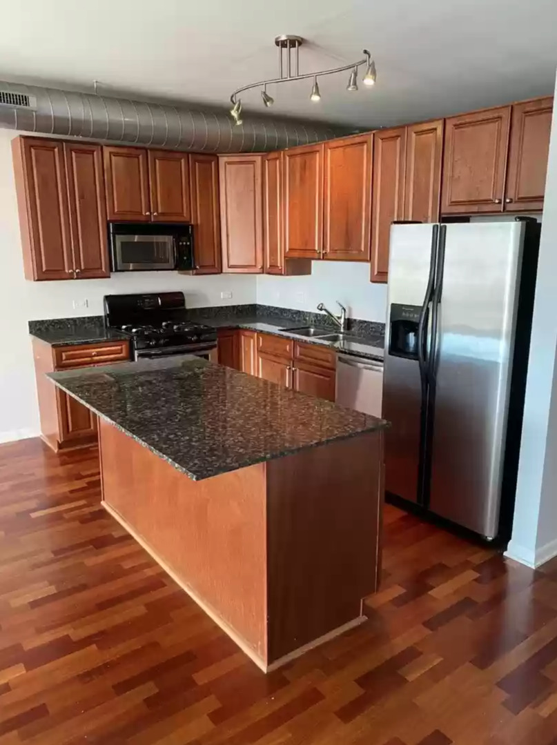 1200 West Monroe Street, Unit 603 Chicago, IL 60607 - Photo 3 of 11 a kitchen with granite countertop wooden cabinets a stove a oven and a refrigerator with wooden floor