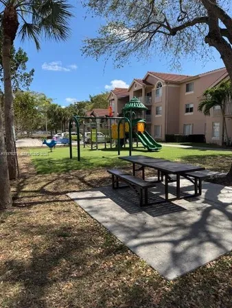 a park view with a table and chairs under an umbrella