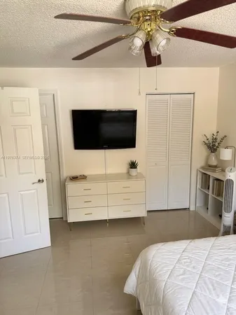a bedroom with a bed a flat screen tv and chandelier