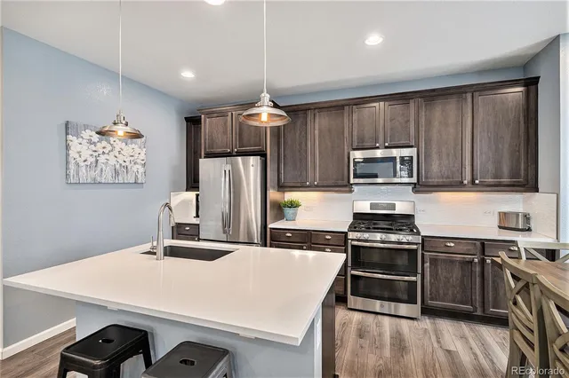 a kitchen with kitchen island a counter space a sink appliances and cabinets