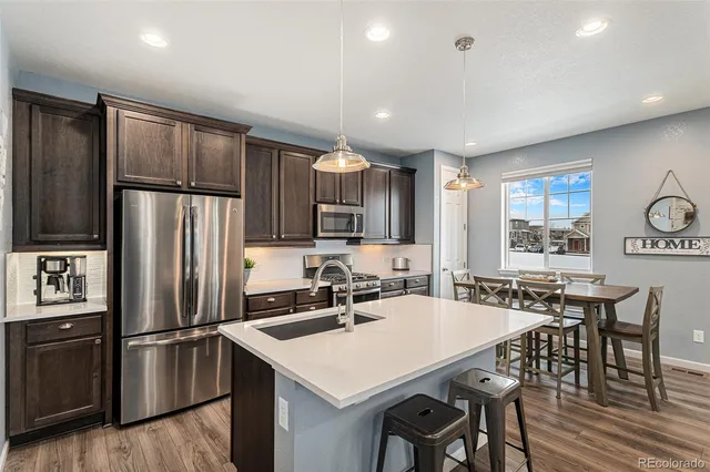 a kitchen with refrigerator a sink and chairs