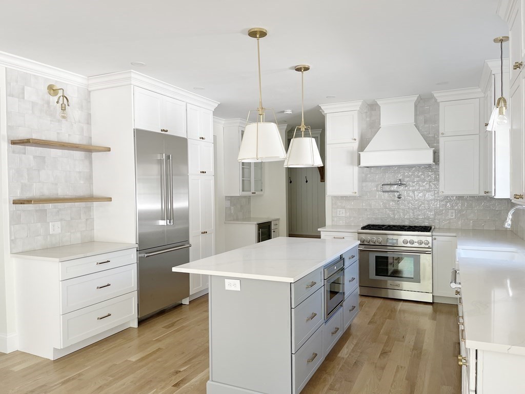 18 Libby Avenue Reading, MA 01867 - Photo 12 of 23 a kitchen with stainless steel appliances a stove a refrigerator and white cabinets