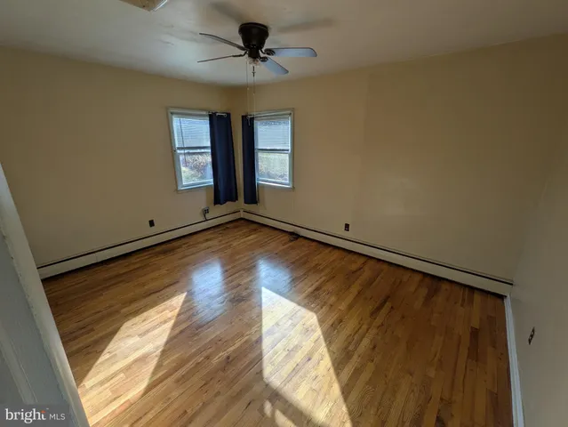 a view of empty room with wooden floor and fan