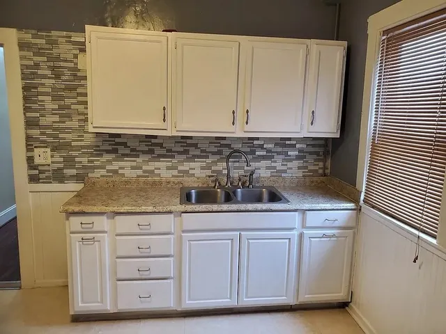 a kitchen with granite countertop a sink and cabinets