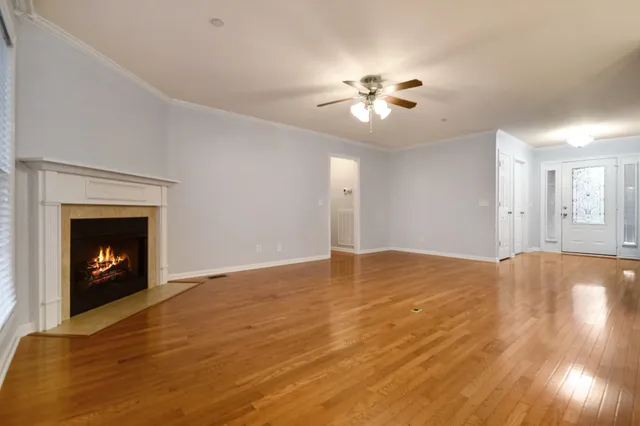 a view of an empty room with wooden floor and a fireplace