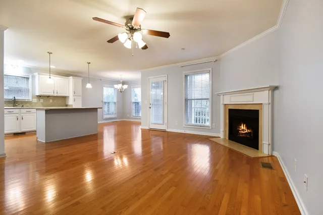 a view of an empty room with wooden floor and a kitchen