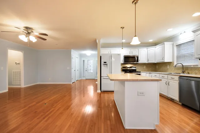 a kitchen with stainless steel appliances granite countertop a sink a stove a refrigerator and island with wooden floor