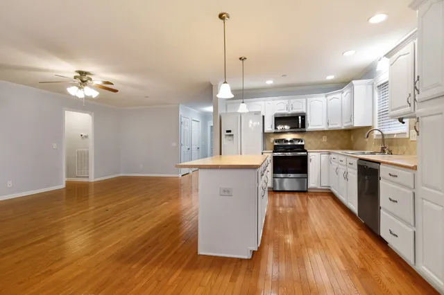 a kitchen with kitchen island white cabinets and stainless steel appliances