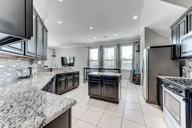 a kitchen with stainless steel appliances granite countertop a stove a sink and a refrigerator