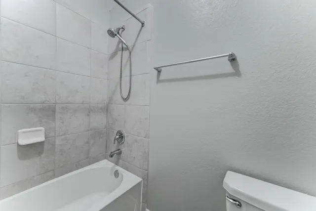 a bath tub sitting next to a white toilet and a shower