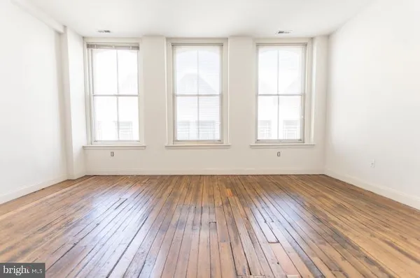 an empty room with wooden floor and windows
