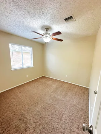 an empty room with a window and a ceiling fan