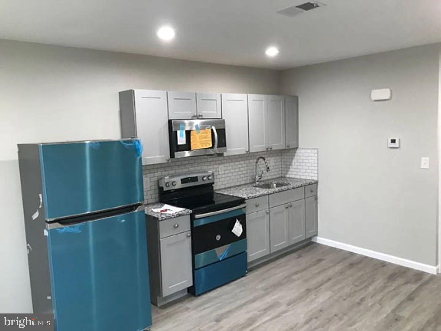 228 South Edgewood Street Philadelphia, PA 19139 - Photo 7 of 15 a kitchen with granite countertop stainless steel appliances and wooden cabinets