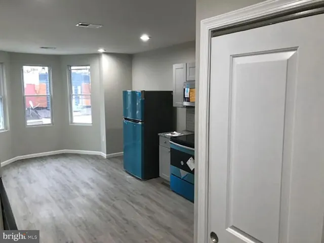 a view of a kitchen with refrigerator and wooden floor