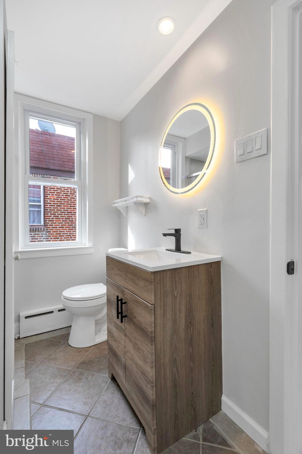 4938 State Road Drexel Hill, PA 19026 - Photo 19 of 38 a bathroom with a toilet a sink a mirror and a window