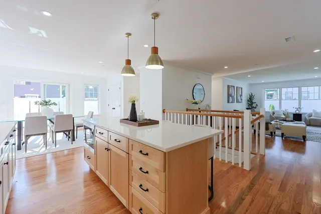 a open kitchen with stainless steel appliances granite countertop a stove top oven a dining table and chairs with wooden floor