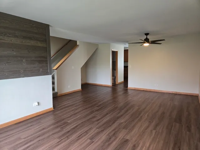 a view of a room with wooden floors and ceiling fan