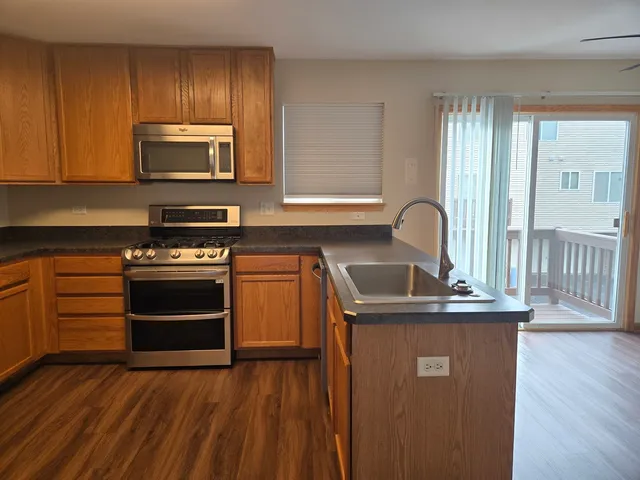 a kitchen with granite countertop a stove a sink and a microwave