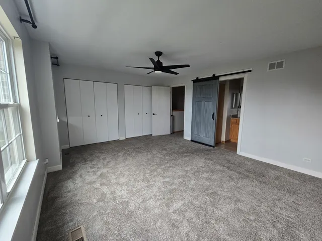 an empty room with a ceiling fan and window