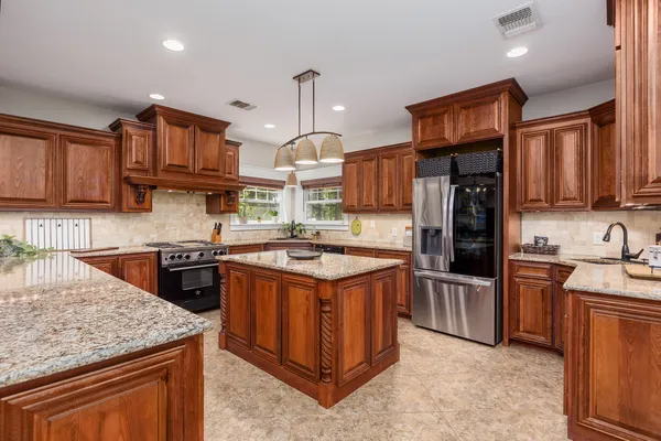 a kitchen with stainless steel appliances granite countertop a stove a sink dishwasher a refrigerator and a oven with wooden floor