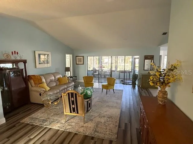 a living room with furniture large window and wooden floor