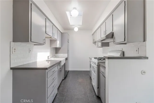 a kitchen with stainless steel appliances granite countertop a sink a stove and a refrigerator