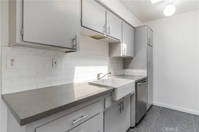 a kitchen with a sink dishwasher and white cabinets with wooden floor