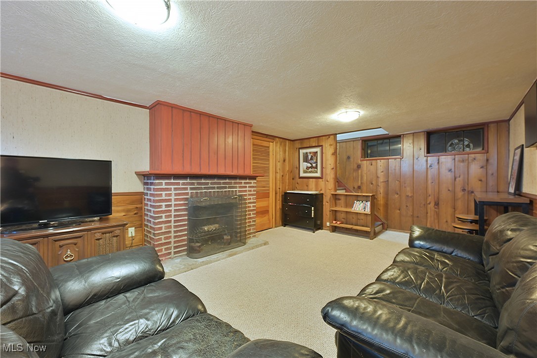 21887 Eaton Road Cleveland, OH 44126 - Photo 27 of 34 Living room with a textured ceiling, carpet floors, a brick fireplace, wood walls, and ornamental molding
