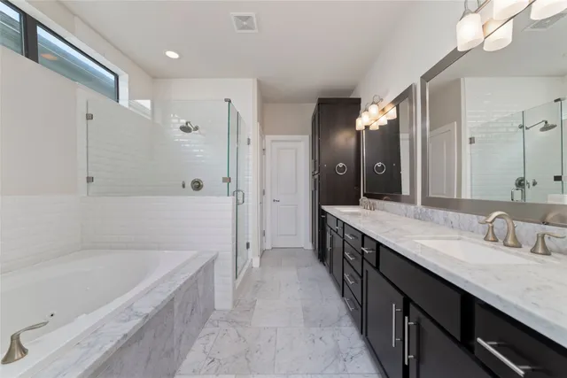 a bathroom with a granite countertop double vanity sink a mirror and a bathtub