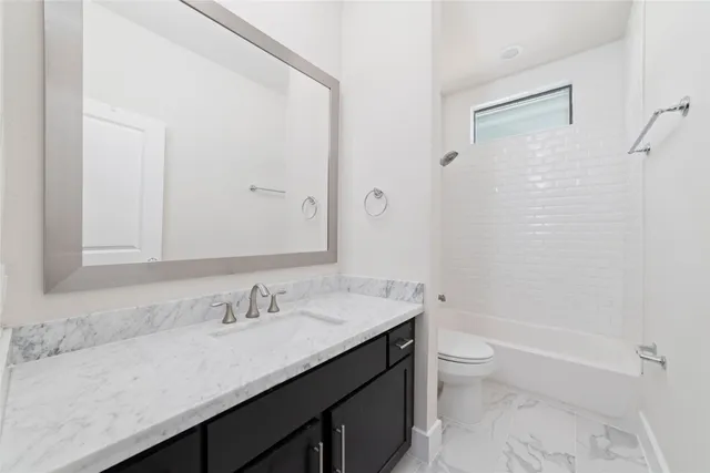 a bathroom with a granite countertop sink a toilet and shower