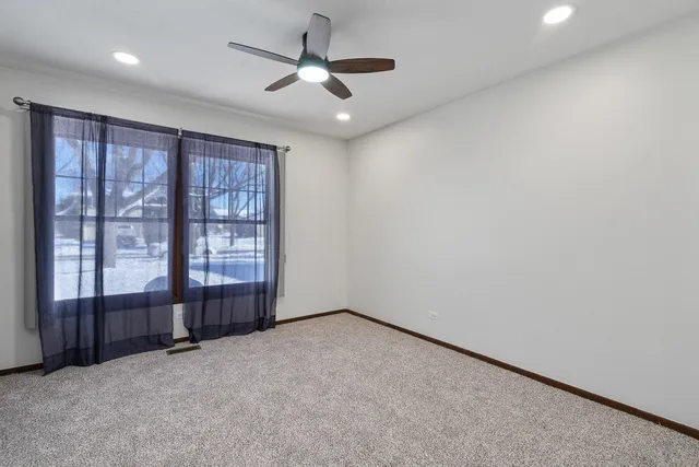 an empty room with windows and fan