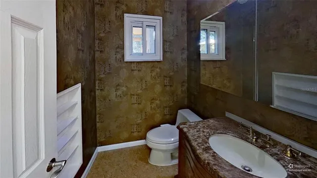 a bathroom with a granite countertop toilet a sink and mirror