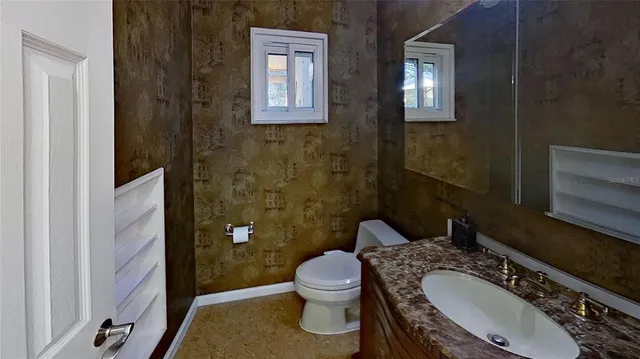 a bathroom with a granite countertop toilet a sink and mirror