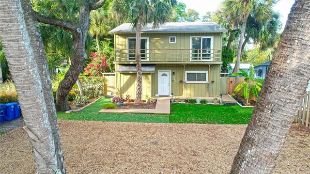 a front view of a house with a yard and potted plants