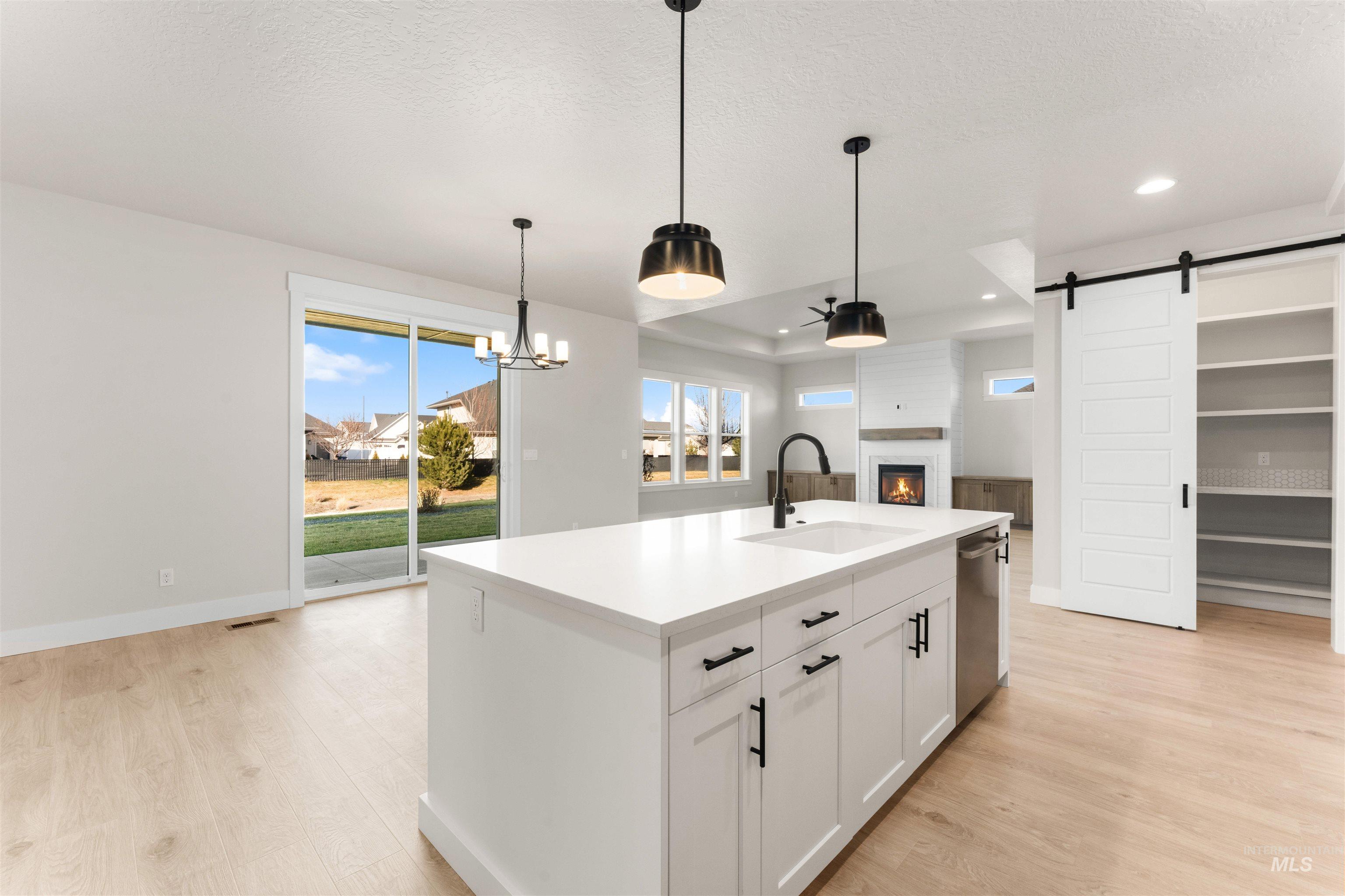 8076 Tandy Cv Street Middleton, ID 83644 - Photo 41 of 41 Kitchen with a barn door, light wood-style floors, an island with sink, open floor plan, and white cabinets