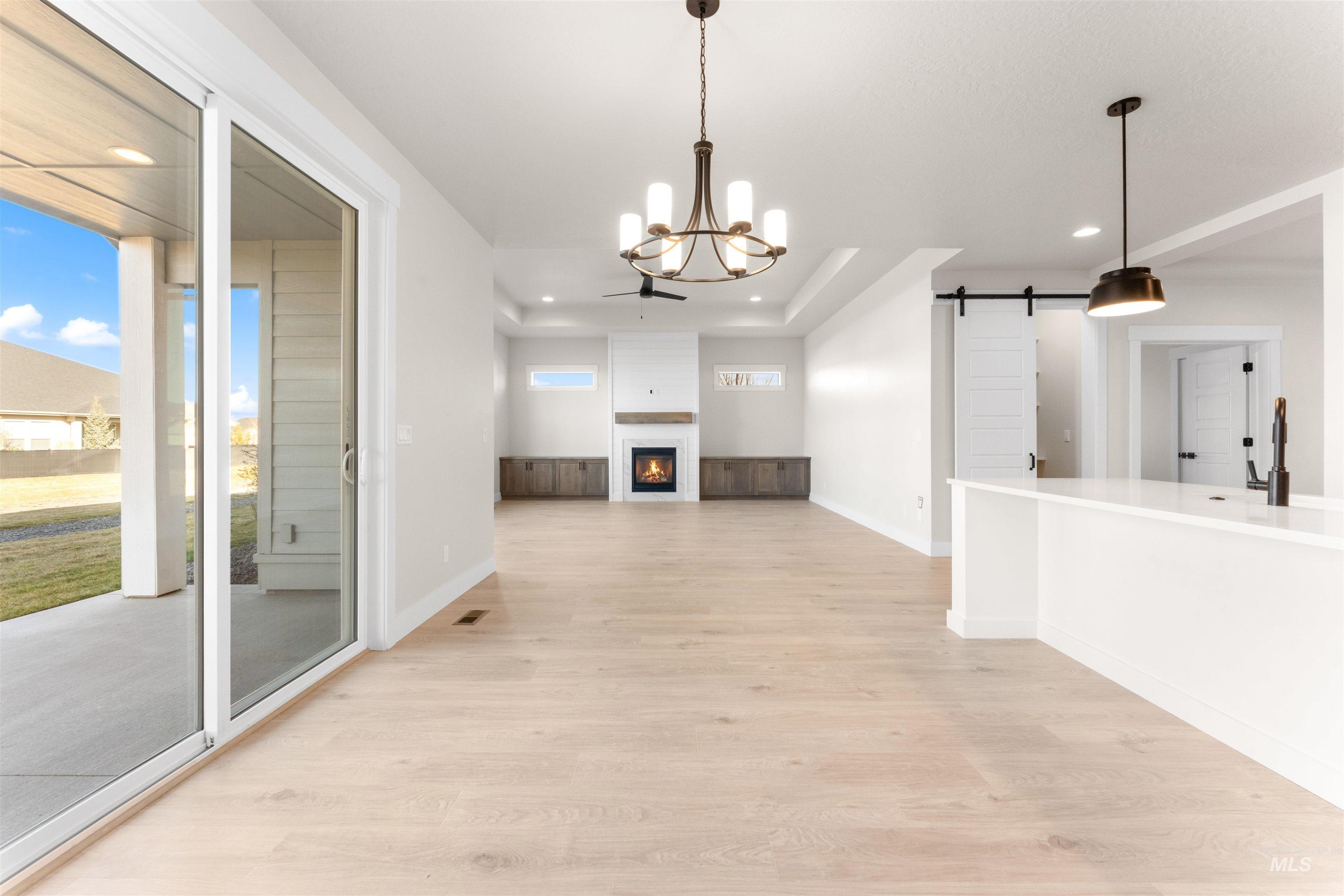 8076 Tandy Cv Street Middleton, ID 83644 - Photo 14 of 41 Unfurnished dining area with a barn door, hanging lights, light wood-style floors, a fireplace, and healthy amount of natural light