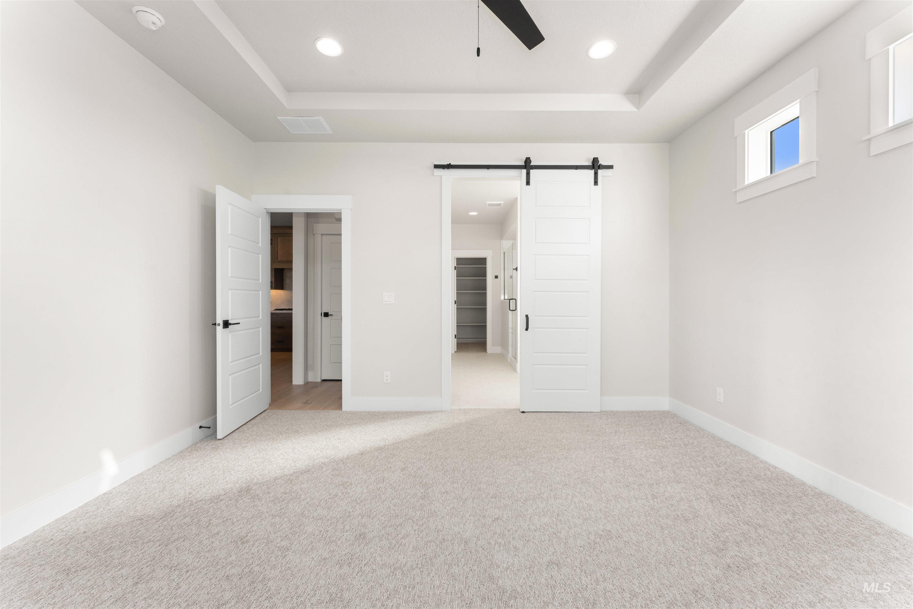 8076 Tandy Cv Street Middleton, ID 83644 - Photo 19 of 41 Unfurnished bedroom with a barn door, a tray ceiling, recessed lighting, light carpet, and ceiling fan