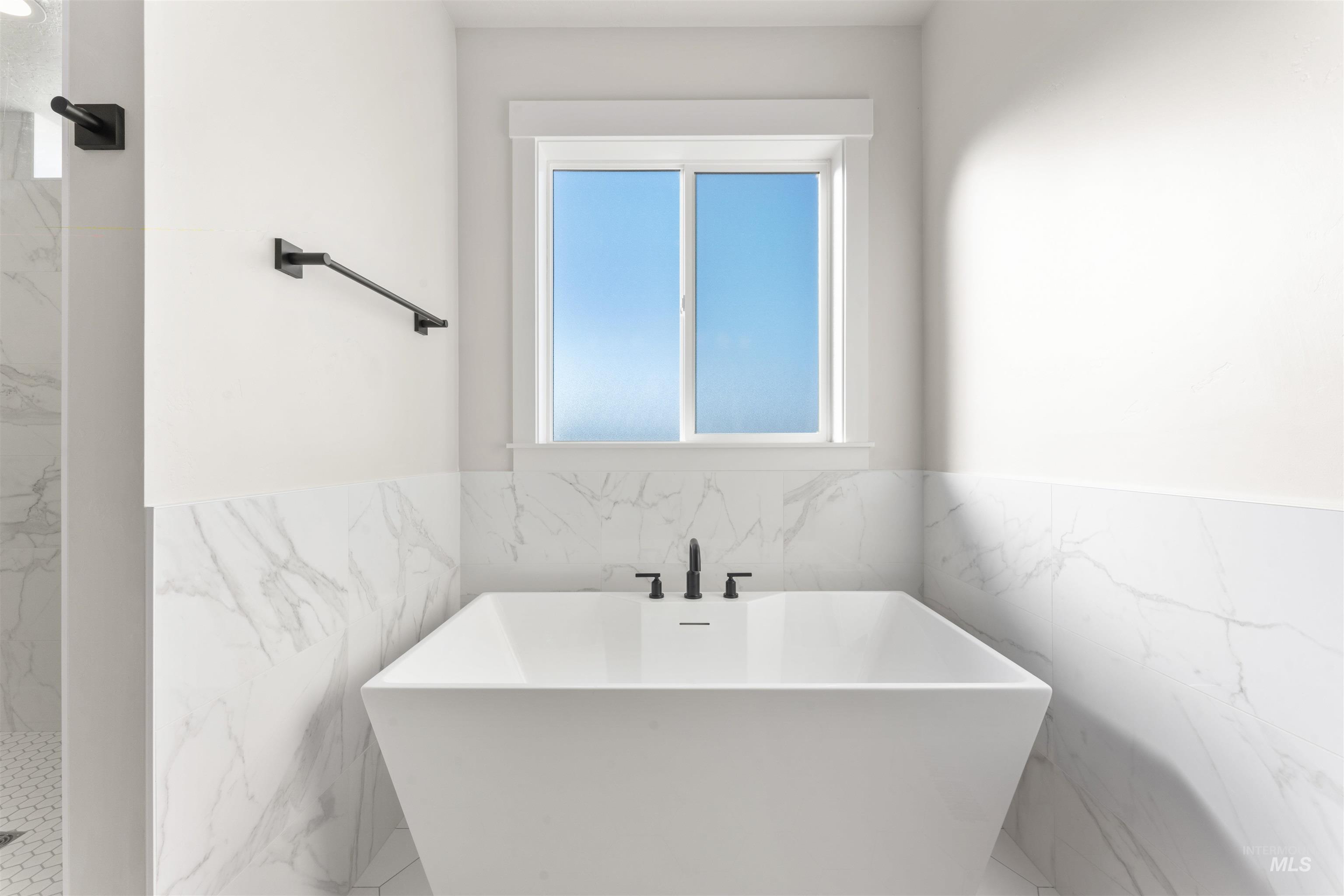 8076 Tandy Cv Street Middleton, ID 83644 - Photo 22 of 41 Bathroom with a wainscoted wall, a freestanding tub, a marble finish shower, and tile walls