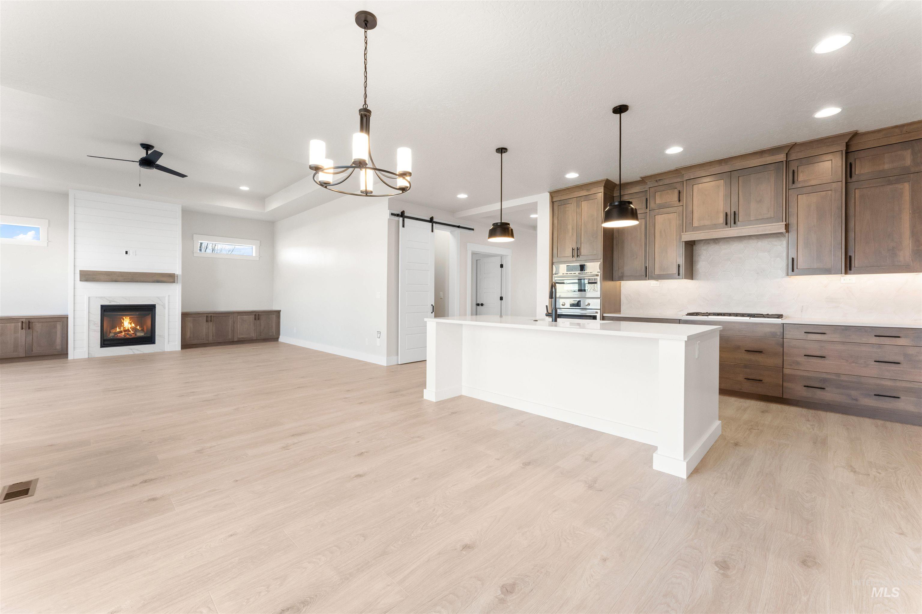 8076 Tandy Cv Street Middleton, ID 83644 - Photo 40 of 41 Kitchen with a barn door, open floor plan, a center island with sink, ceiling fan, and wood finish cabinets