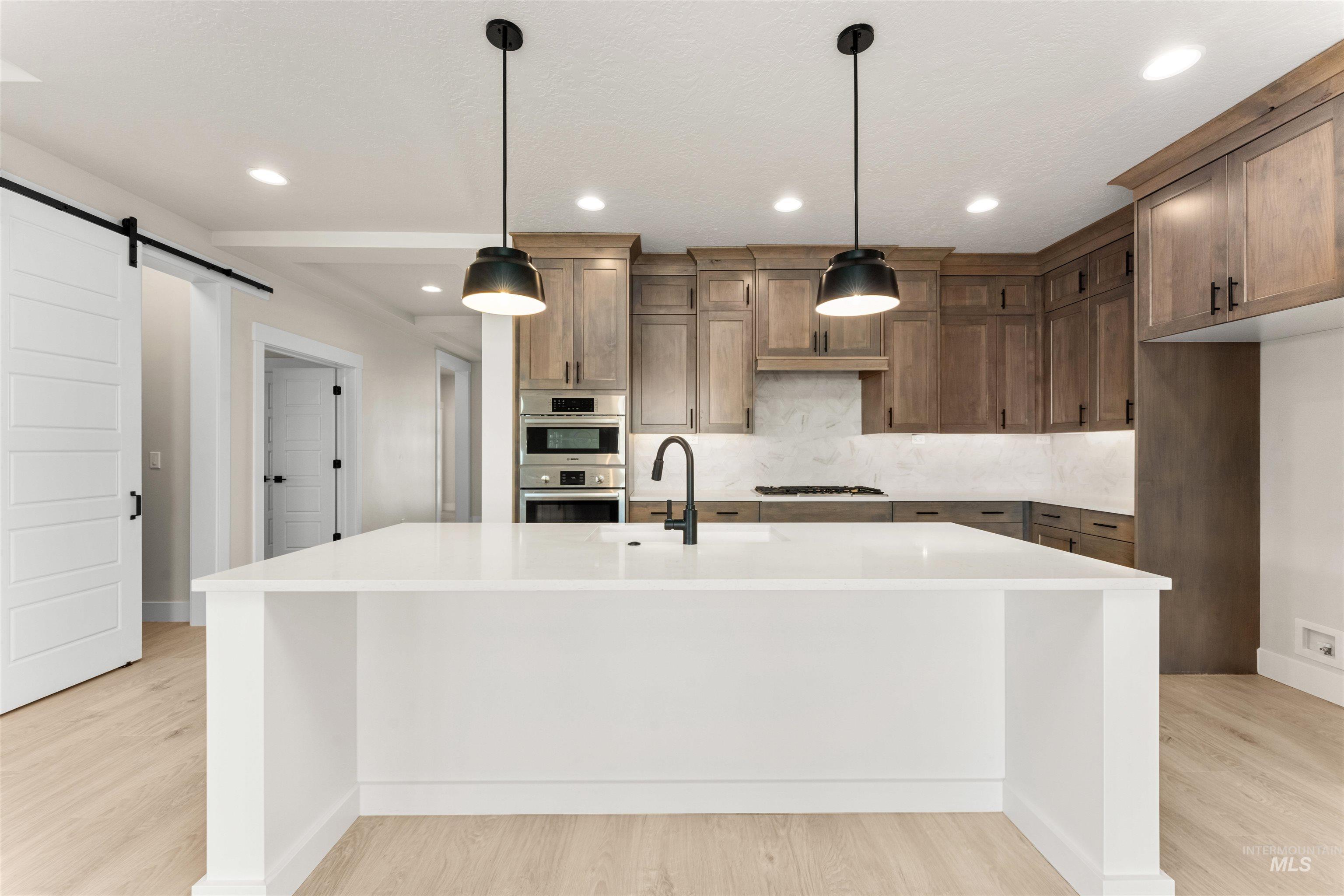 8076 Tandy Cv Street Middleton, ID 83644 - Photo 6 of 41 Kitchen with a barn door, light stone countertops, a center island with sink, and light wood finished floors