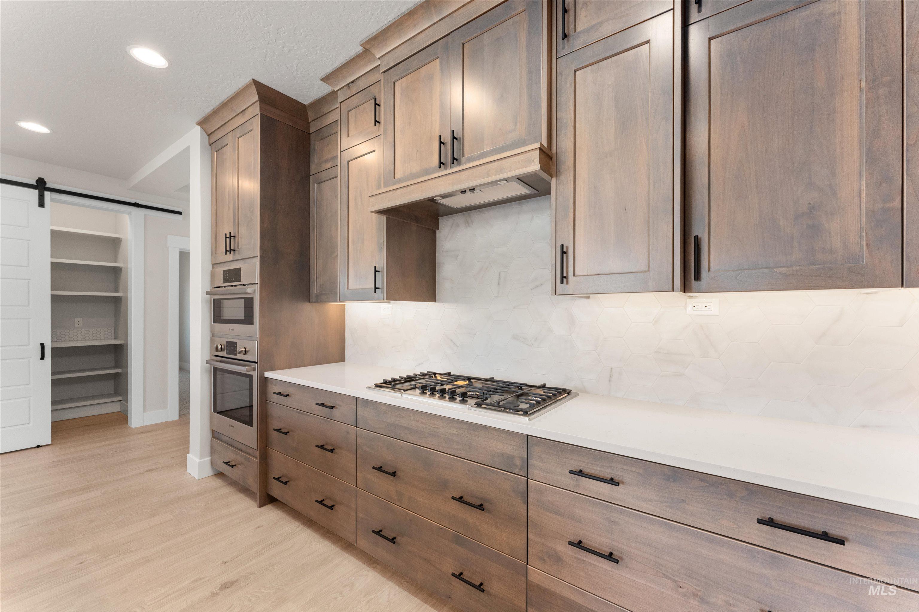 8076 Tandy Cv Street Middleton, ID 83644 - Photo 8 of 41 Kitchen featuring a barn door, backsplash, light wood-style flooring, stainless steel appliances, and recessed lighting