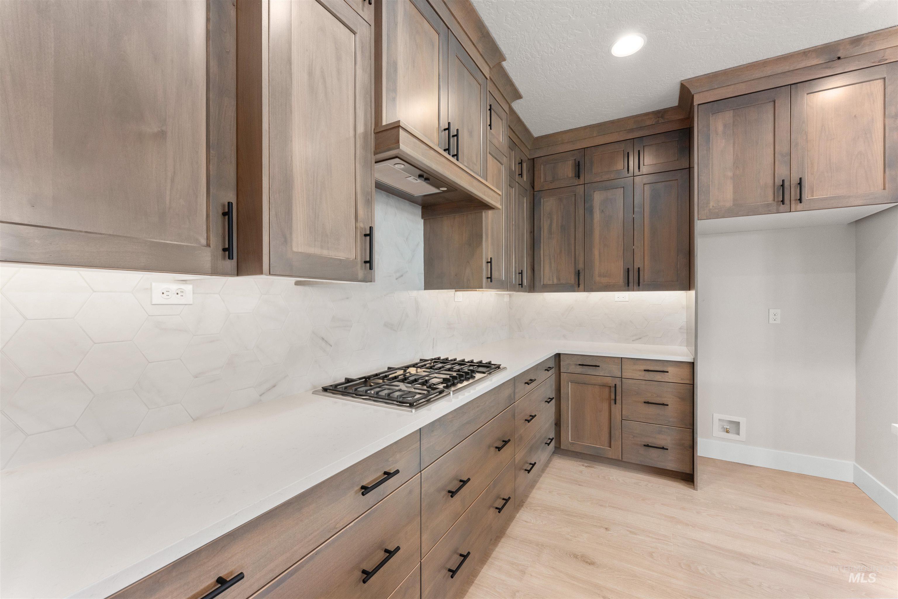 8076 Tandy Cv Street Middleton, ID 83644 - Photo 9 of 41 Kitchen with decorative backsplash, light wood-style flooring, stainless steel gas stovetop, a textured ceiling, and light stone countertops